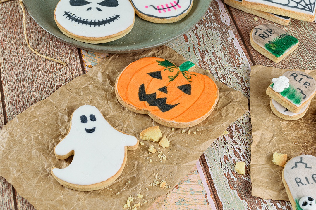 Vários biscoitos amanteigados com tema de Halloween, ao lado de migalhas