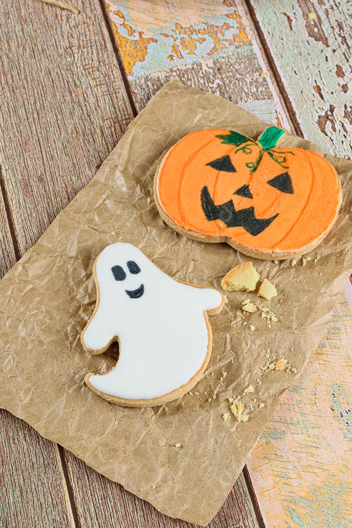Halloween themed shortbread cookies next to crumbs on brown paper