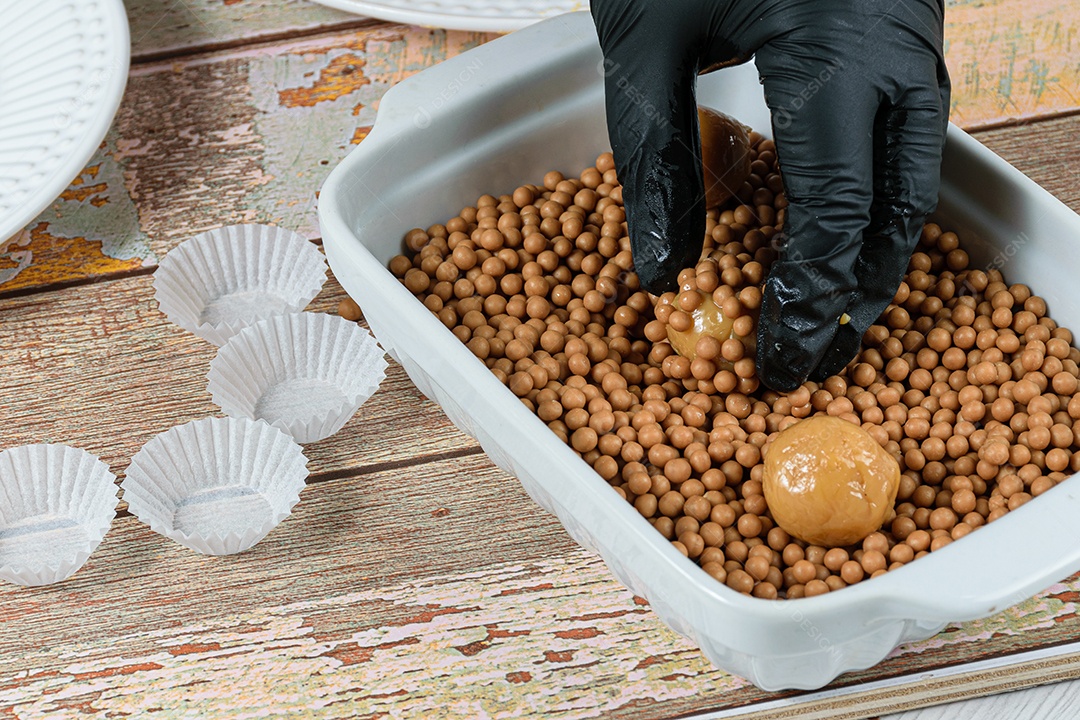 Confeiteiro enrolando o brigadeiro de doce de leite