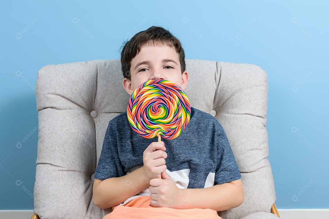 Brasileira de 8 anos com um grande pirulito colorindo e sentada na poltrona