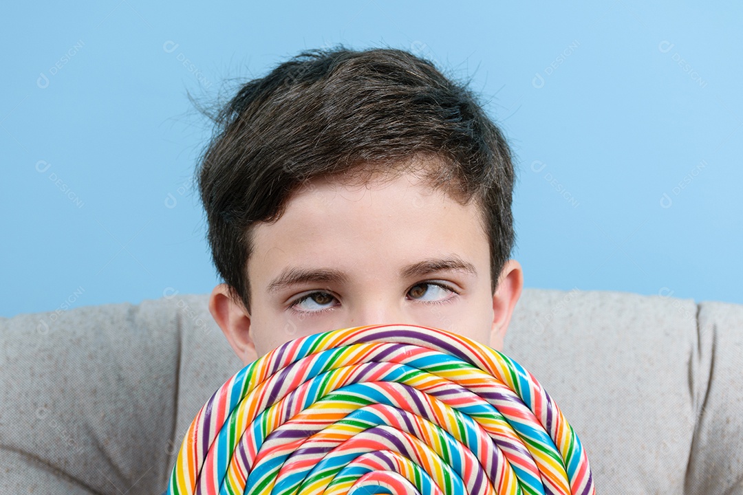 Closeu de uma criança de 8 anos com um olhar vesgo e segurando um pirulito