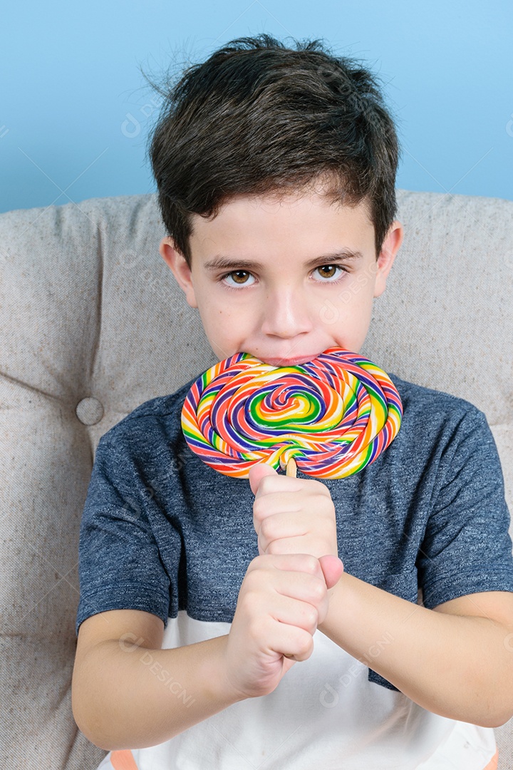 criança de 8 anos mordendo um grande pirulito colorido