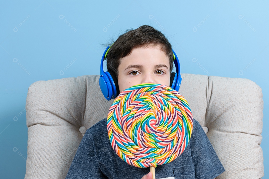 Criança de 8 anos com fones de ouvido e um grande pirulito colorido