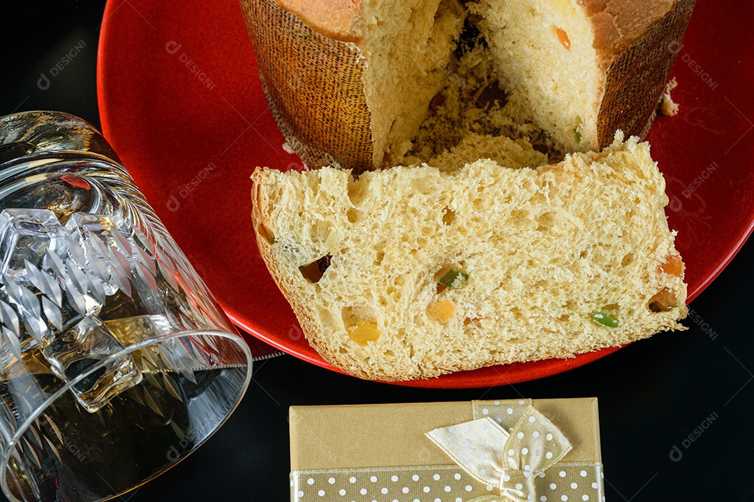 Detalhe de uma fatia de Panettone ao lado de um copo virado