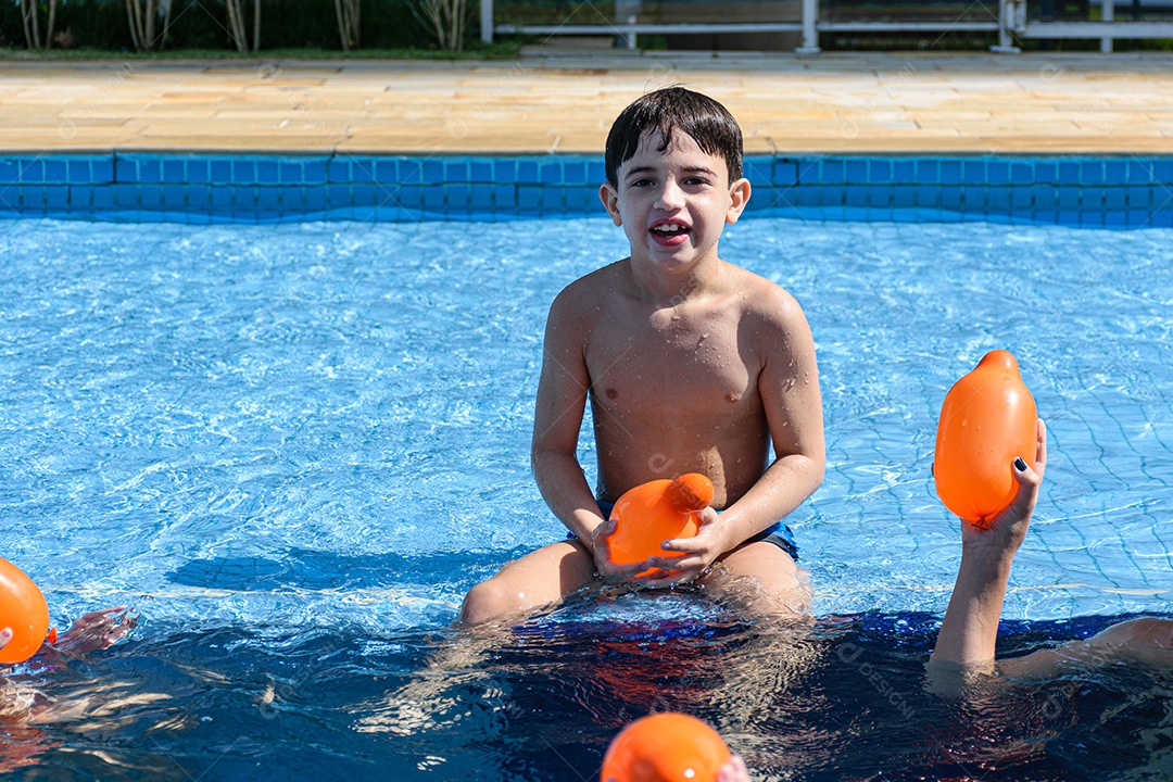 Criança de 8 anos sentada na beira da piscina com a boca aberta