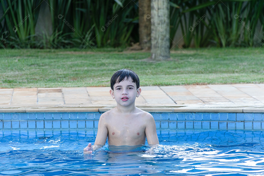 Criança de 8 anos na piscina, esperando a bola ser lançada para ele