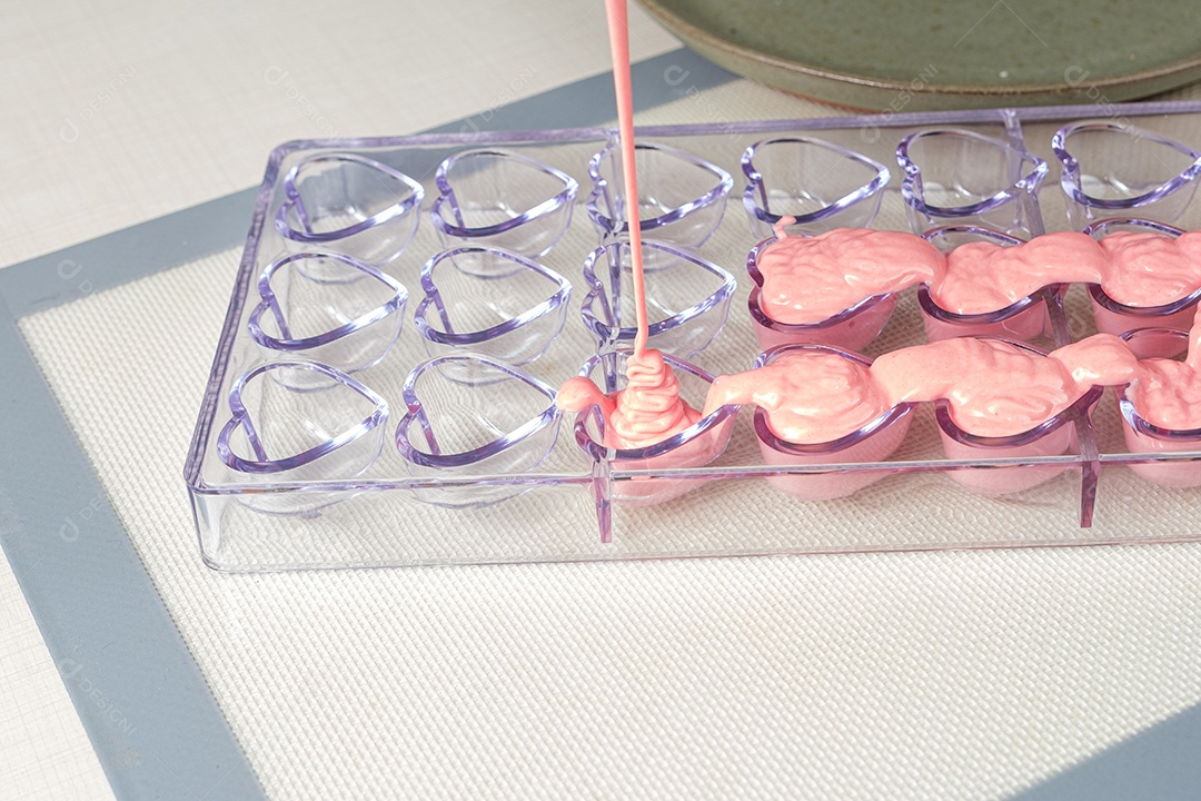 Closeup de ganache de morango sendo derramado em forma de policarbonato