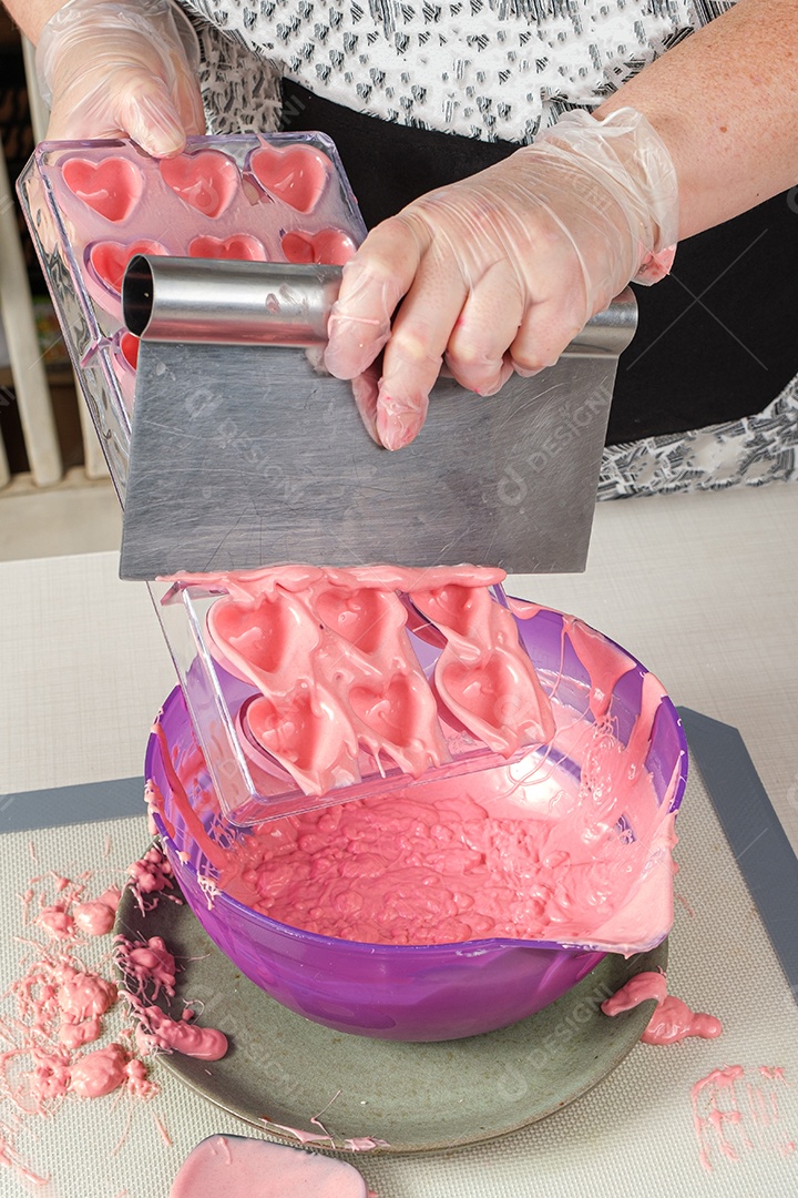 Confeiteiro usando uma espátula para remover o excesso de ganache de morango