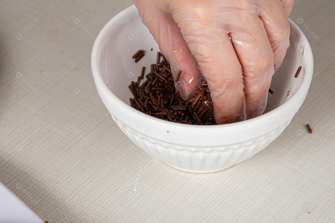 mão do confeiteiro colocando granulado de chocolate