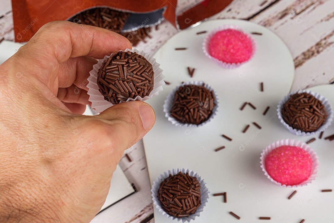 Foco seletivo. Mão masculina pegando um brigadeiro.