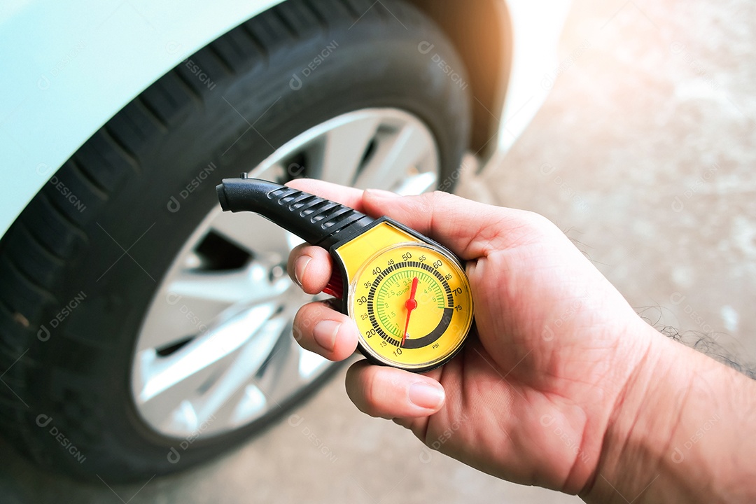 O motorista está segurando um medidor de pressão de pneu padrão na mão