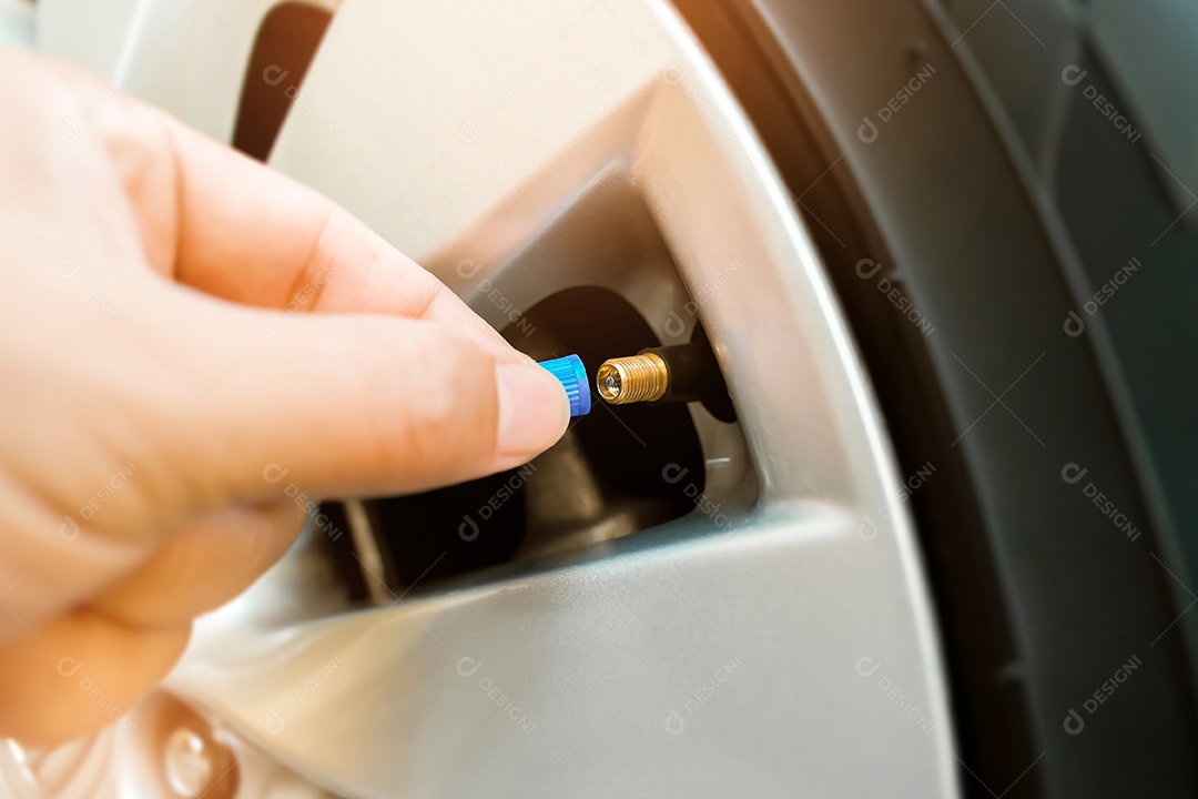 O motorista está colocando a tampa da válvula do pneu da roda de um carro