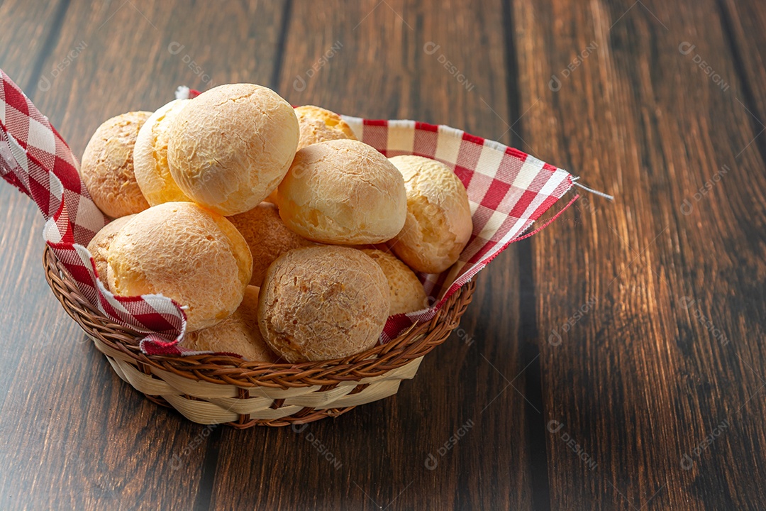 Pão de queijo em recipiente em forma de coração na mesa de madeira