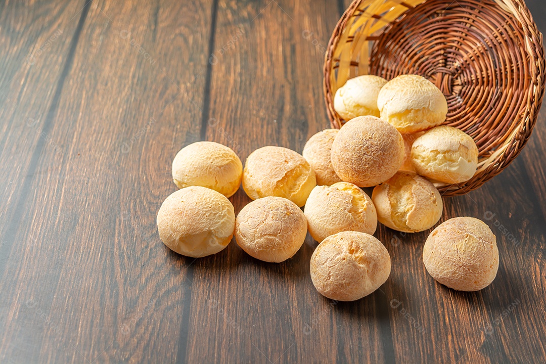 Pão de queijo em recipiente em forma de coração na mesa de madeira com copo