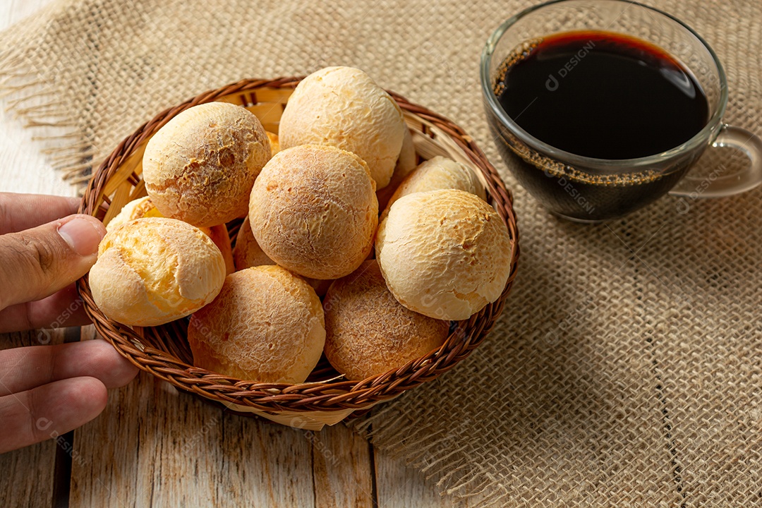 Homem serve pão de queijo na mesa de madeira, tradicional brasileiro