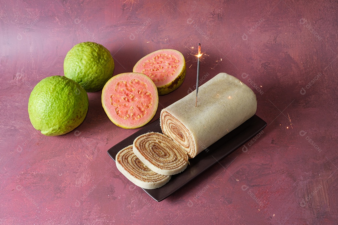 Detalhe da chama de uma vela brilha sobre um bolo de rolo fatiado