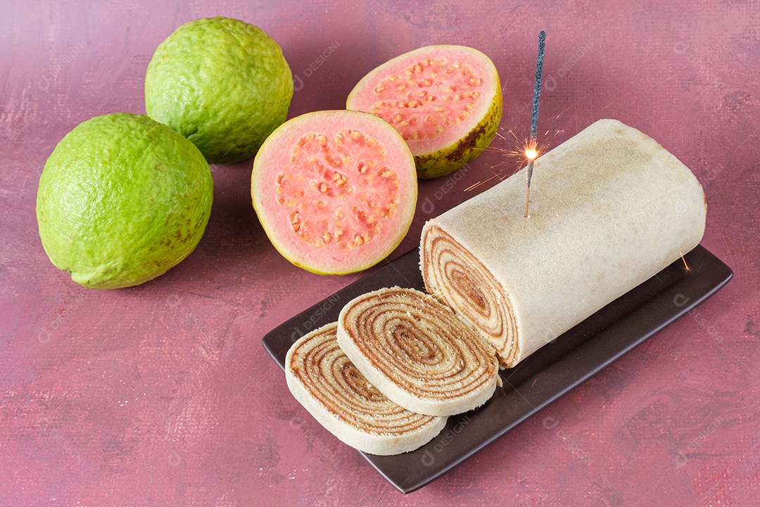 Detalhe da chama de uma vela brilha sobre um bolo de rolo fatiado