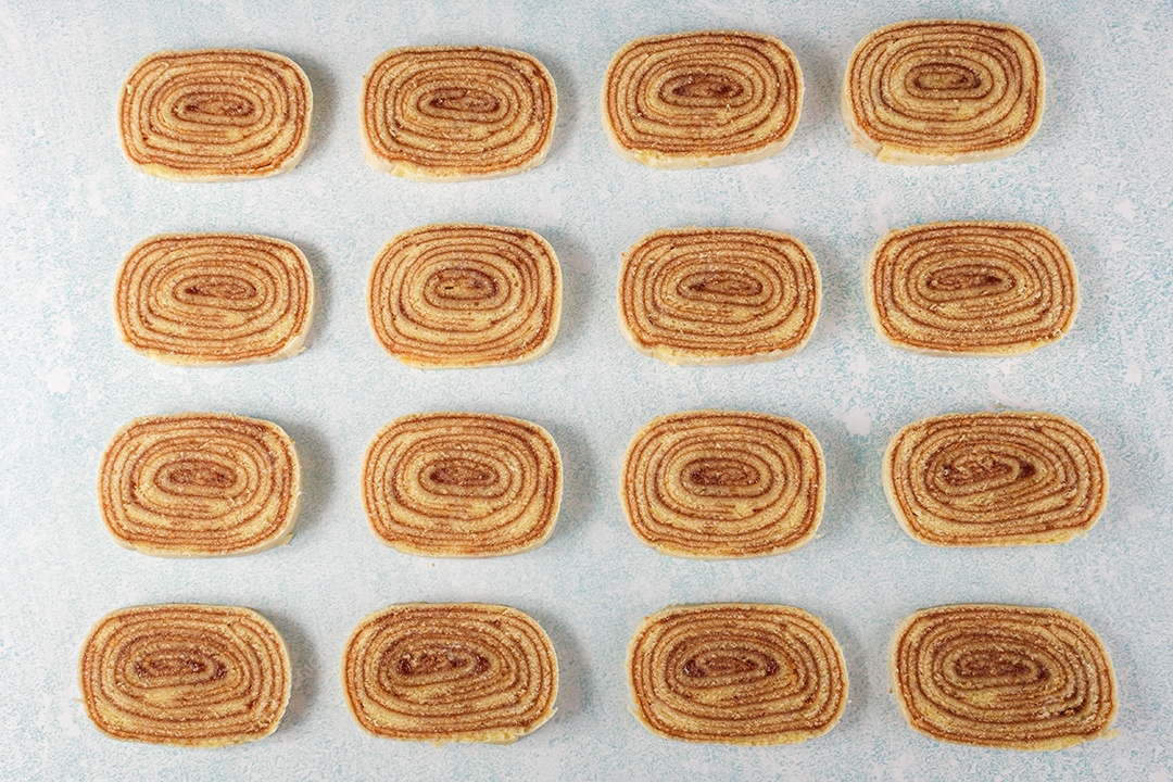 Várias fatias de bolo de rolo alinhadas em um fundo azul e branco