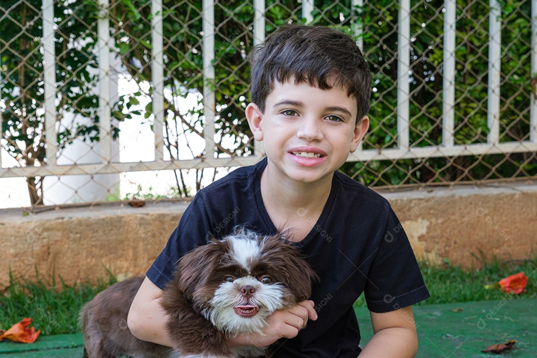 Brasileiro de 8 anos no jardim com seu primeiro animal de estimação, um filhote de shih tzu.