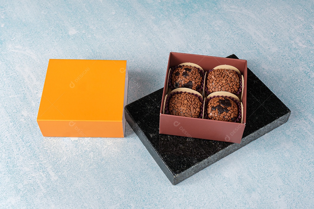 Brigadeiros dentro de uma caixa em uma pedra de mármore