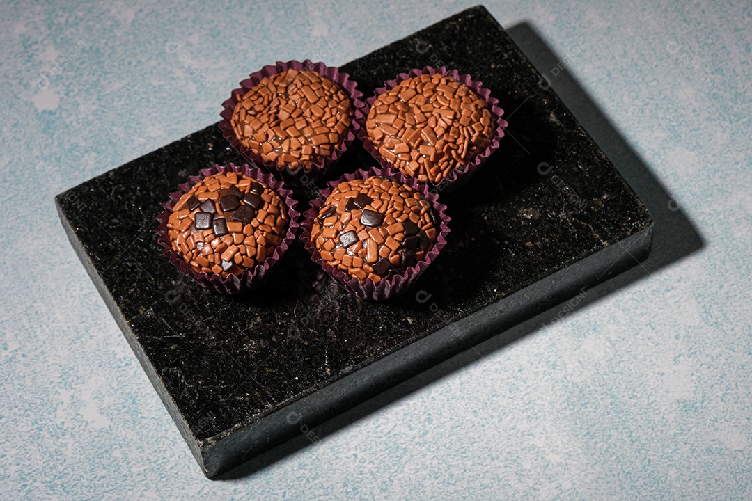 Brigadeiros arranjados em uma pedra de mármore preta brilhante