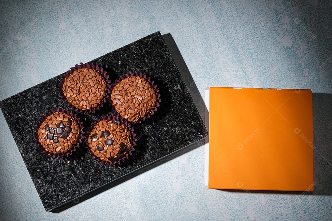 Brigadeiros dispostos sobre pedra de mármore preto brilhante