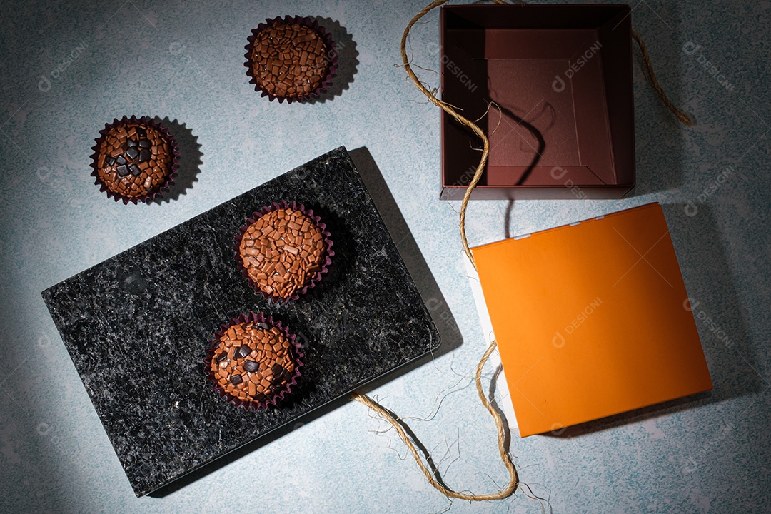 Brigadeiros dispostos sobre pedra de mármore preto brilhante