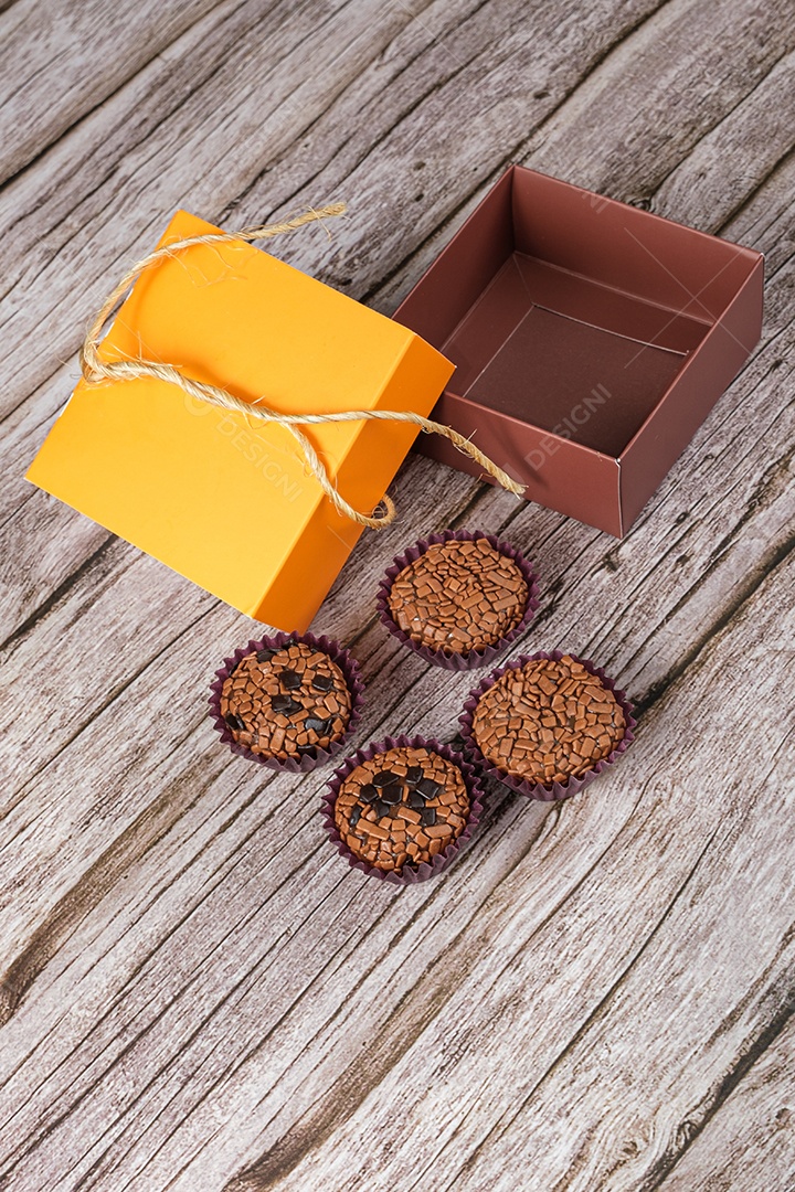 Brigadeiros amargos e tradicionais ao lado de uma caixa aberta