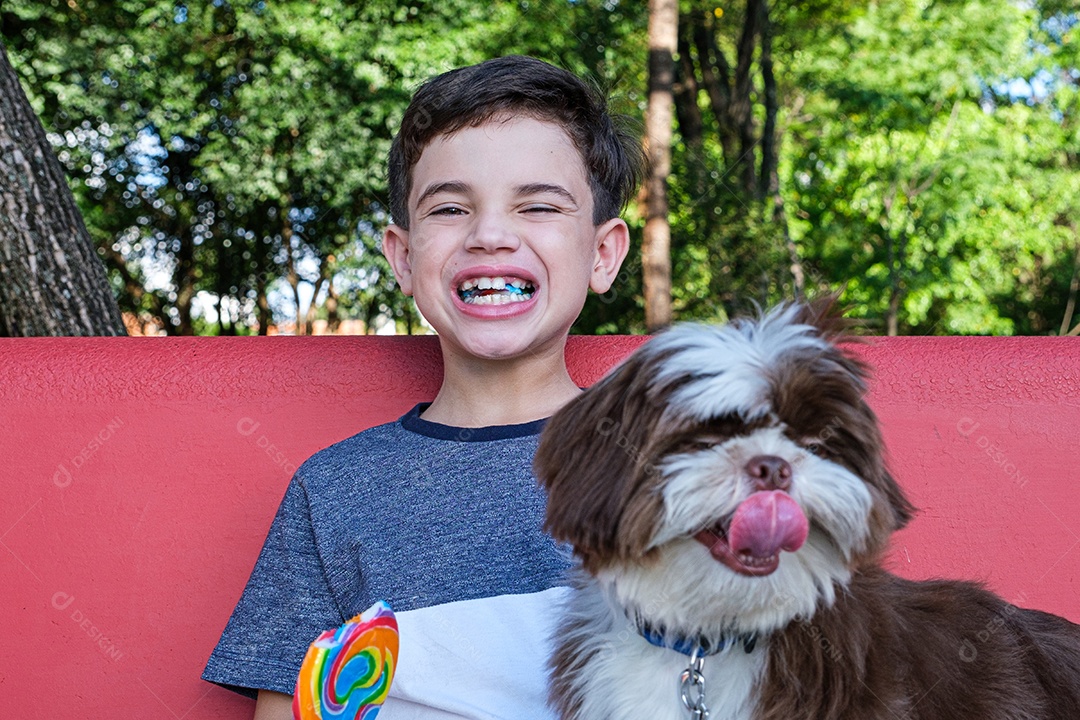Menino de 8 anos mordendo pirulito e sorrindo para a câmera