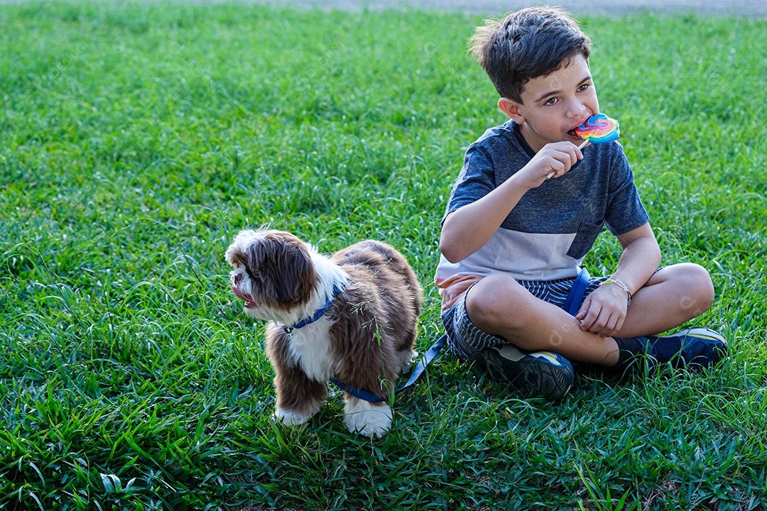 Menino de 8 anos sentado no gramado ao lado de seu animal de estimação