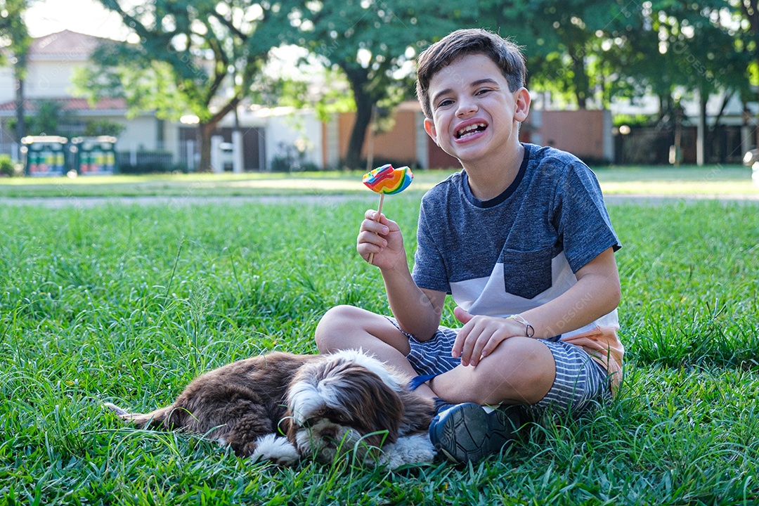 Menino de 8 anos sentado no gramado ao lado de seu animal de estimação