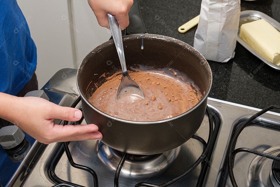 Closeup das mãos da criança mexendo com uma colher para fazer brigadeiro