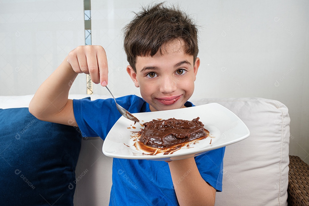 Criança de 8 anos no sofá segurando um prato de brigadeiro