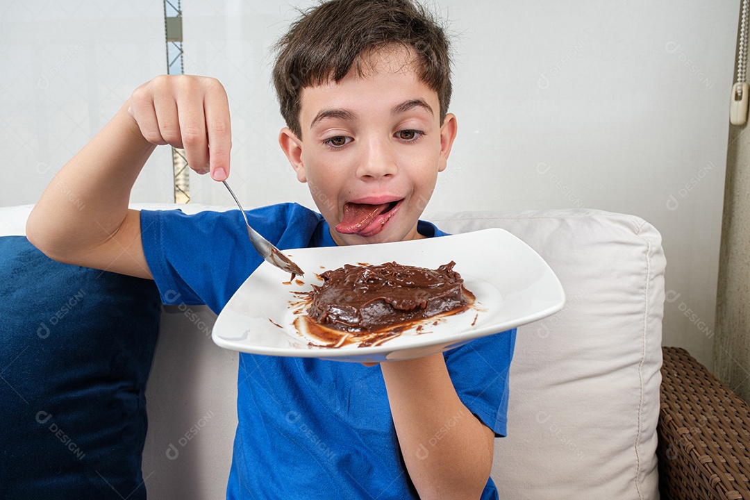 Criança de 8 anos no sofá segurando um prato de brigadeiro