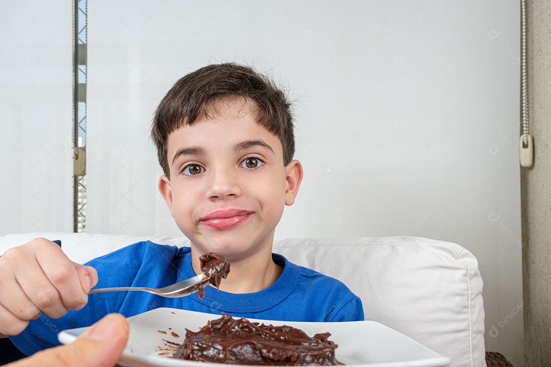 Criança de 8 anos segurando uma colher com brigadeiro