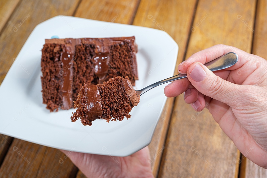 Mulher segurando um prato e mostrando um pedaço de bolo de chocolate