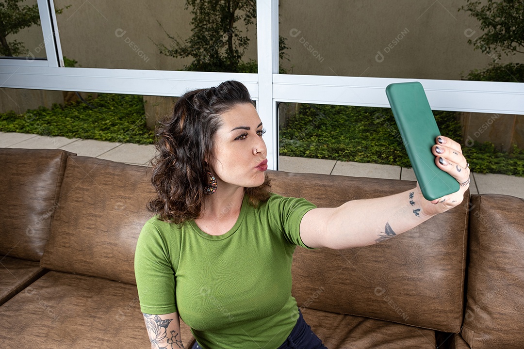 Brasileiro tatuado fazendo biquinho e tirando selfie.