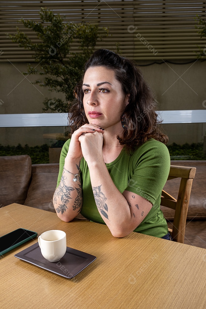 Brasileira tatuada e pensativa, olhando para frente