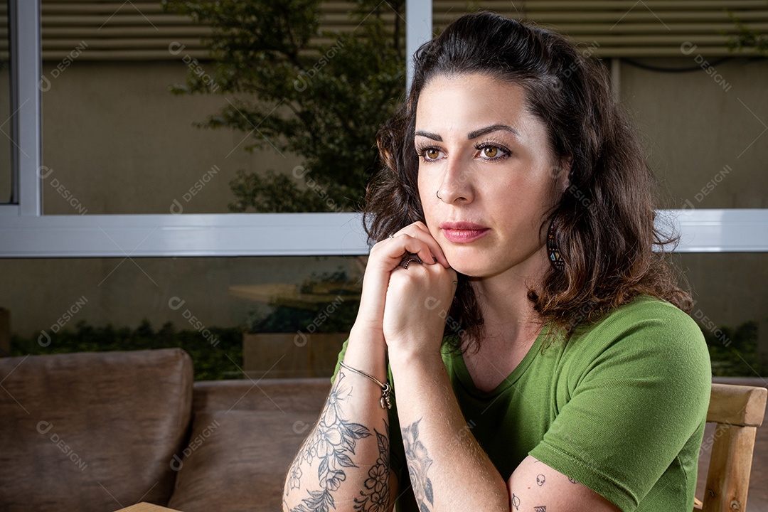 Detalhe da mulher brasileira tatuada e pensativa olhando para a frente