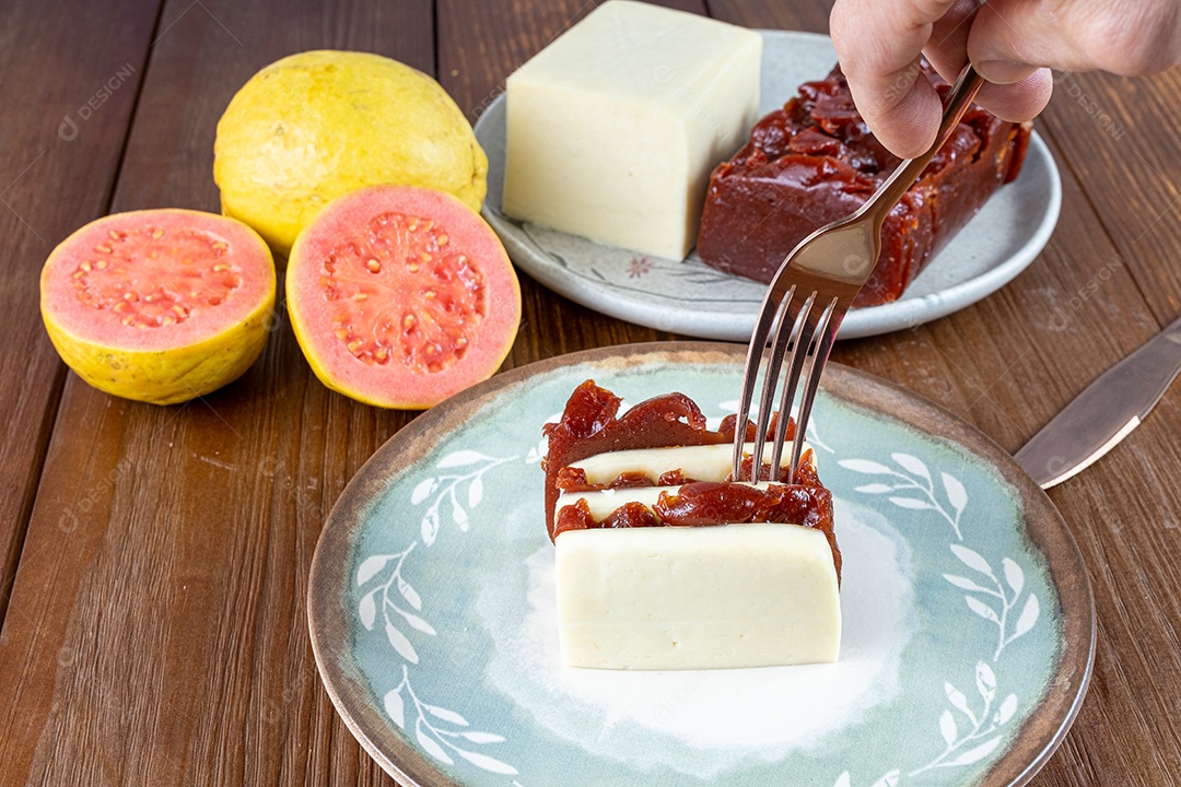 Homem pegando com um garfo, fatias empilhadas de doce de goiaba e requeijão.