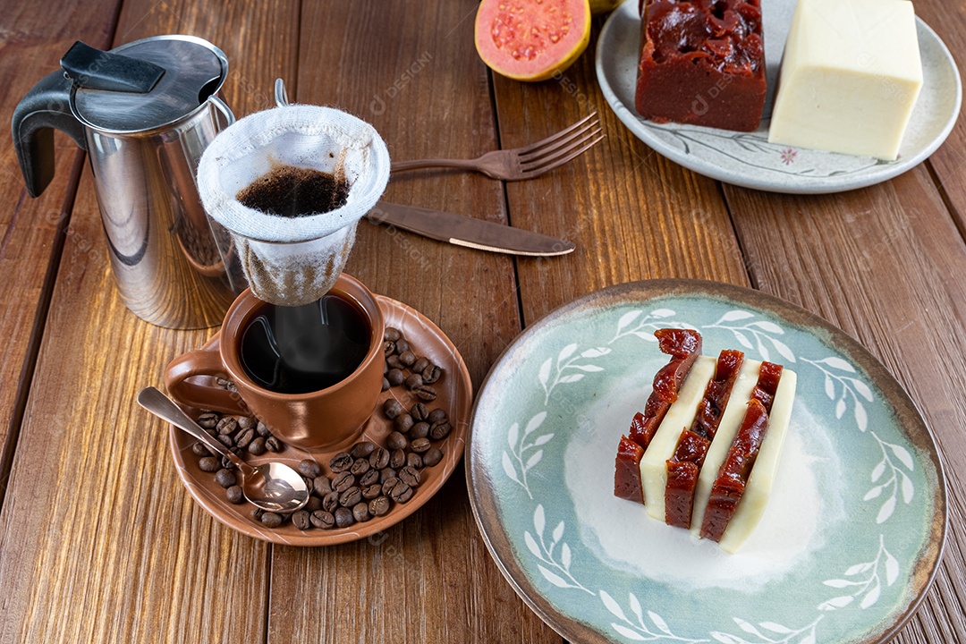 Doce de goiabada e fatias de requeijão ao lado de grãos, xícara e pano