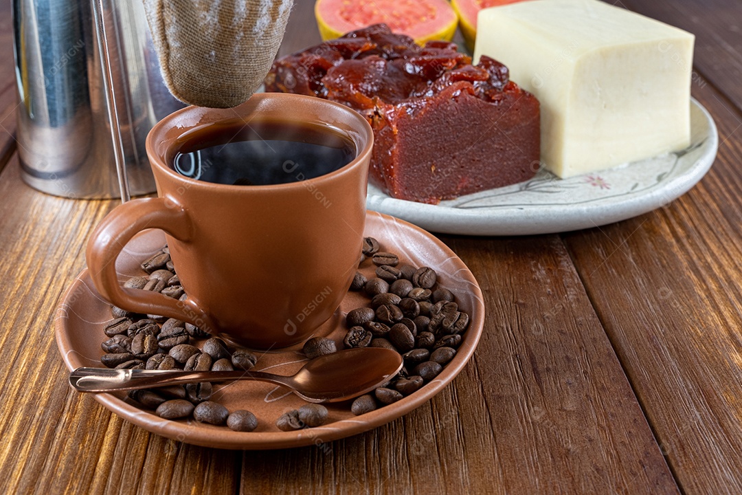 Closeup de grãos de café rodeado por copo, pano de filtro e doce de goiaba e requeijão.
