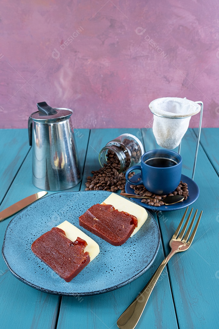 Doce de goiaba com queijo rodeado de talheres, xícara e café