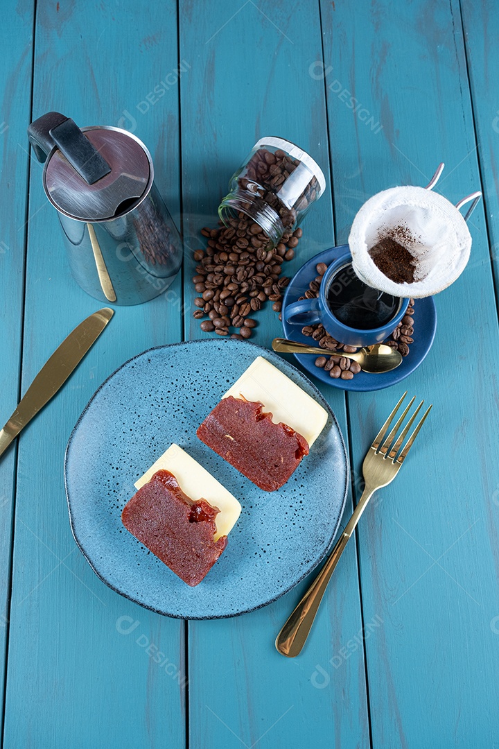 Doce de goiaba com queijo rodeado de talheres, xícara e café