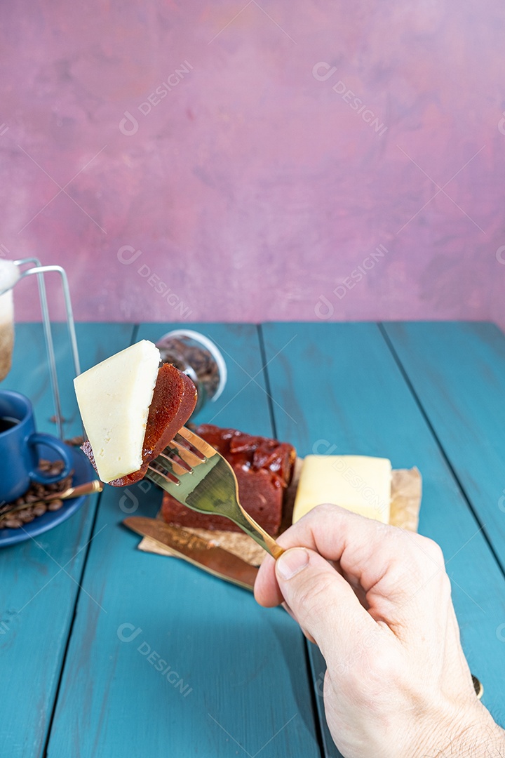Homem segurando um garfo com pedaços de goiabada com queijo