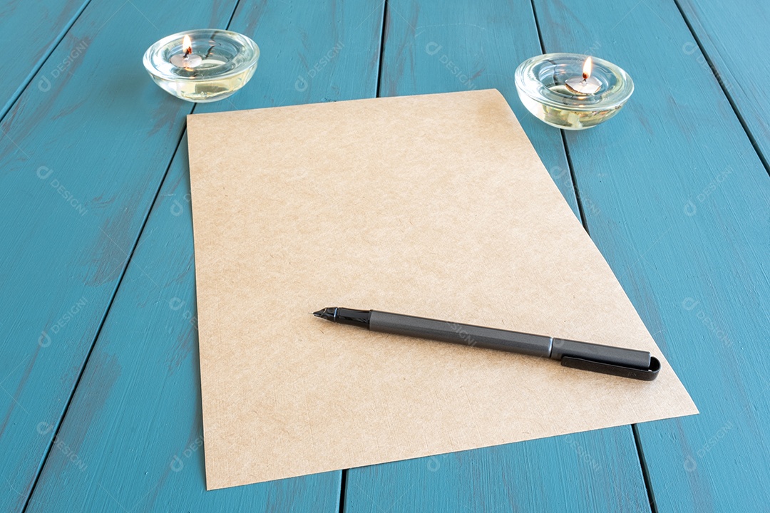 Caneta-tinteiro em papel pardo, ao lado de velas acesas