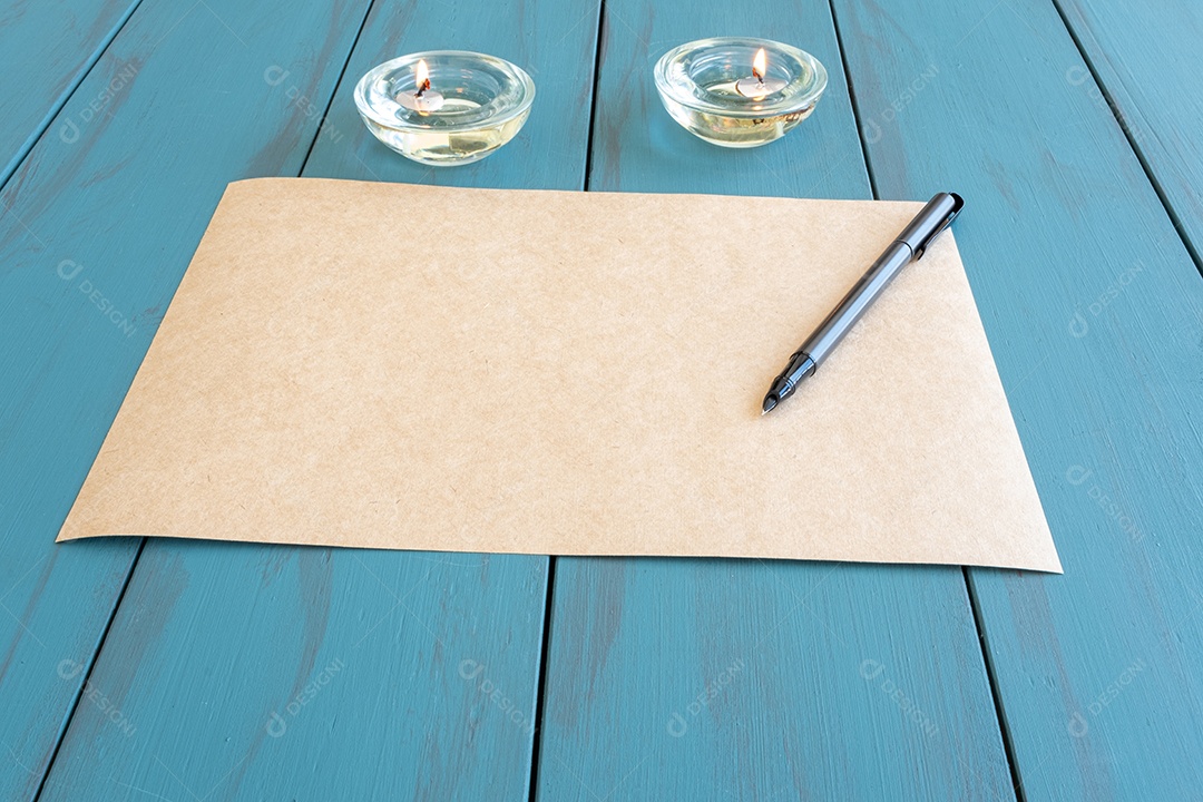 Caneta-tinteiro em papel pardo, ao lado da vista acesa do lado das velas.