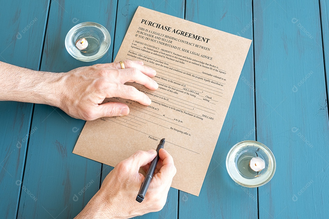 As mãos do homem com caneta-tinteiro assinando contrato ao lado de velas acesas