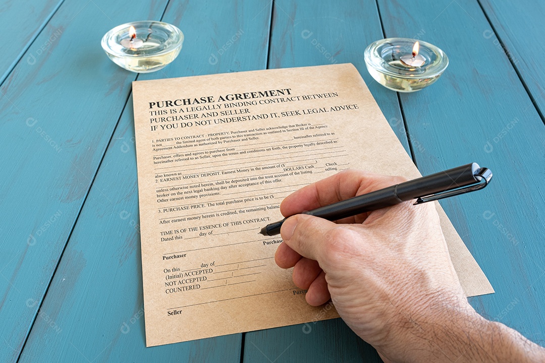 A mão do homem com caneta-tinteiro assinando contrato ao lado de vela acesa