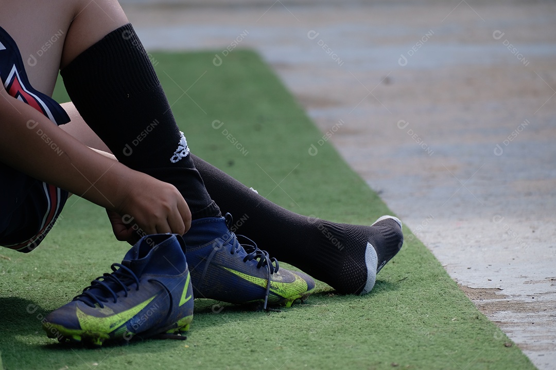 jogador de futebol colocando chuteira